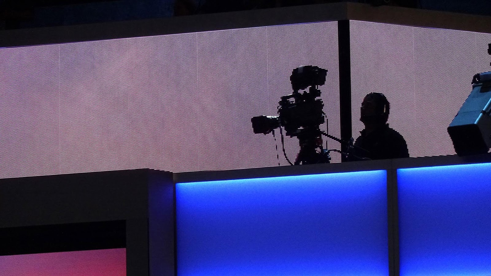 silhouette of camera operator against large LED screen